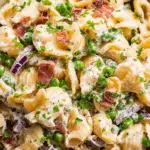 creamy pasta salad with bacon, peas, and red onion in a bowl