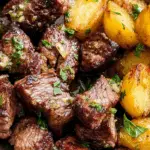 Garlic Butter Steak Bites and Potatoes with golden roasted baby potatoes garnished with parsley.